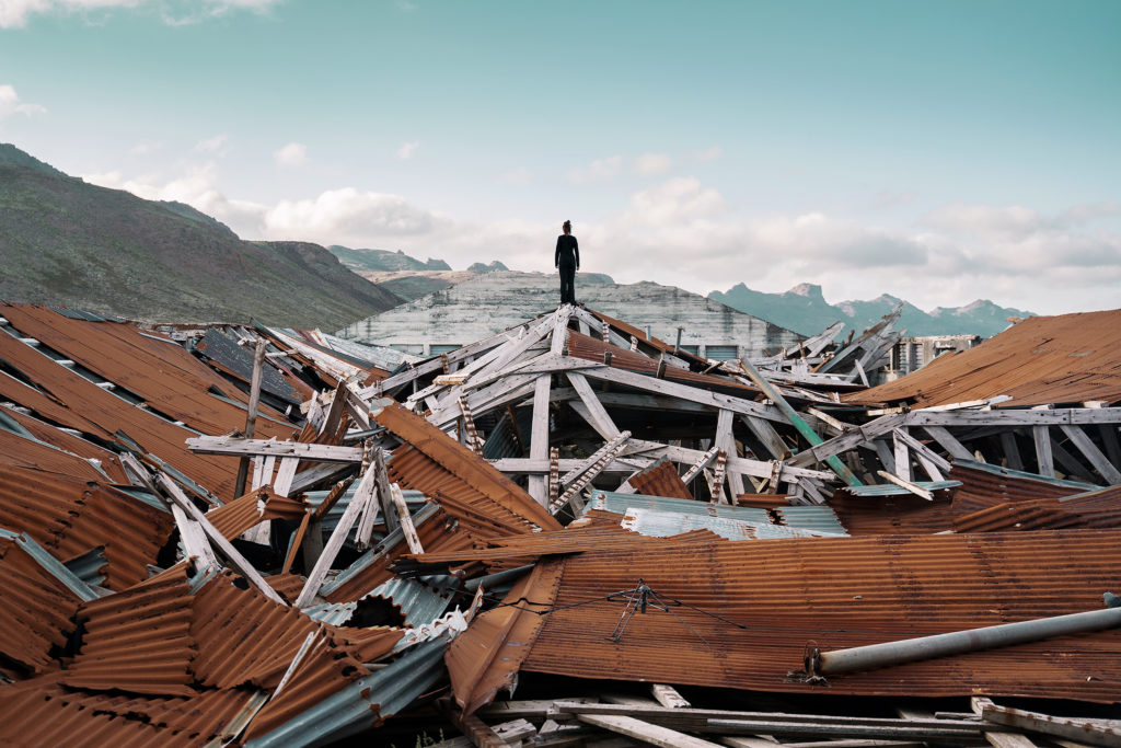 Fine Art Photography taken in Iceland. The artwork shows a solitary figure standing on the ruins of a lost place, looking out over the mountains in the distance.