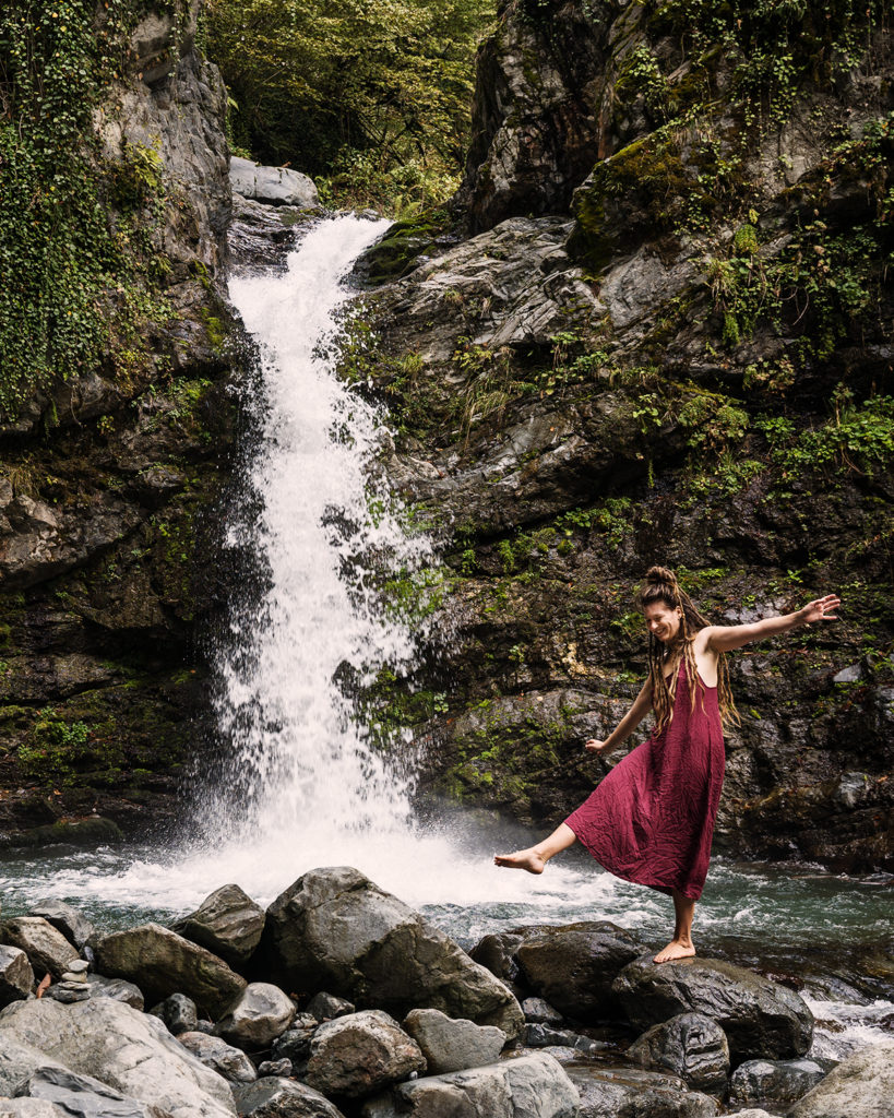 Adventurer and artist Anna Heimkreiter in Georgia in front of a waterfall.